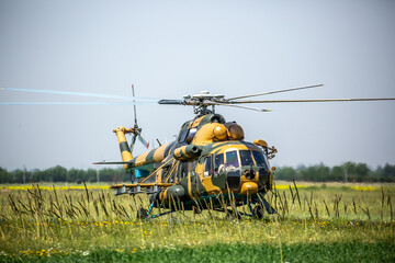 In the field is a military helicopter with soldiers. Armed conflict, fighting. Air armament and...