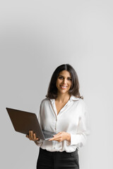Vertical portrait of young middle eastern Israel businesswoman using laptop pc online application for work isolated on white wall. Smiling happy indian, arabic woman in business suit holding computer