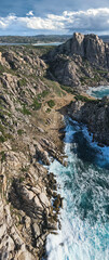 Aerial view of Cala di Mezu and Valle della Luna on Capo Testa, Sardinia, showcases rugged granite cliffs meeting the crashing waves of the turquoise sea. Rocky landscapes blend with lush greenery.