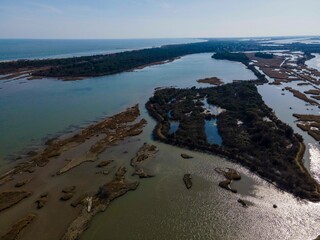 Serene wetlands of the Po Delta with shimmering water channels and scattered islands, forming a vast network of marshes and lagoons rich in wildlife and vegetation.