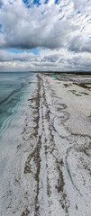 Panoramic shot of Le Saline beach at Le Tonnare in Stintino, Sardinia. The white beach stretches along the turquoise-coloured sea under a dramatic cloud cover.