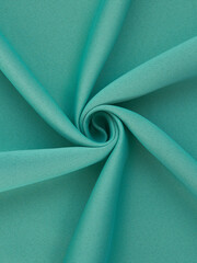 Close-up of twisted sea green curtain fabric texture in smooth folds