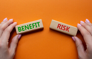Risk or Benefit symbol. Concept word Risk or Benefit on wooden blocks. Businessman hand. Beautiful...