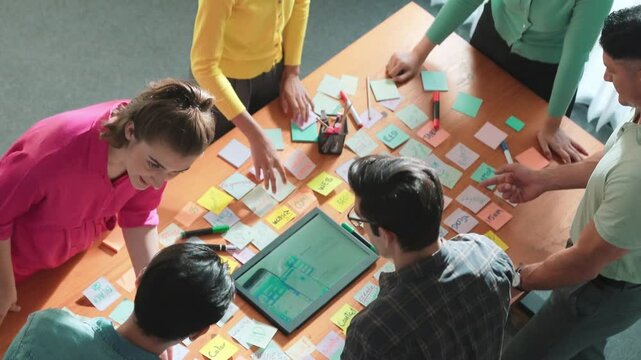 Aerial view of developer team discussing and showing digital program and writing by using Ux Ui design. Top down view of business people develop wireframe prototype for phone and computer. Symposium.