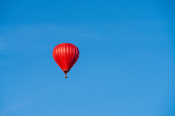 Flying red hot air balloon in the blue sky