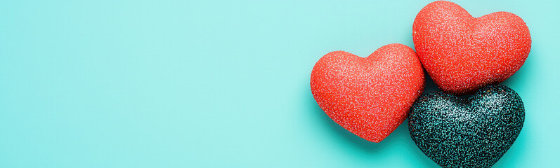 Obraz premium Glittery red and teal hearts on vibrant turquoise background, evoking love and joy