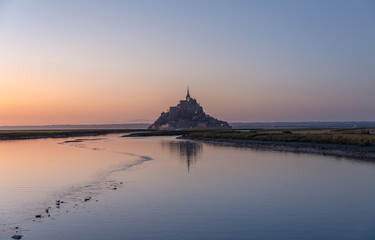 Mont saint Michele at sunset, blue hour. Reflection in the river water.