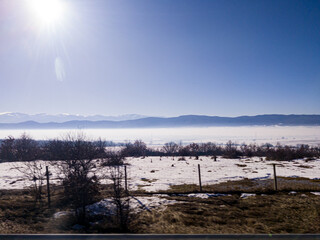 View to field and mountain with fog and snow from highway