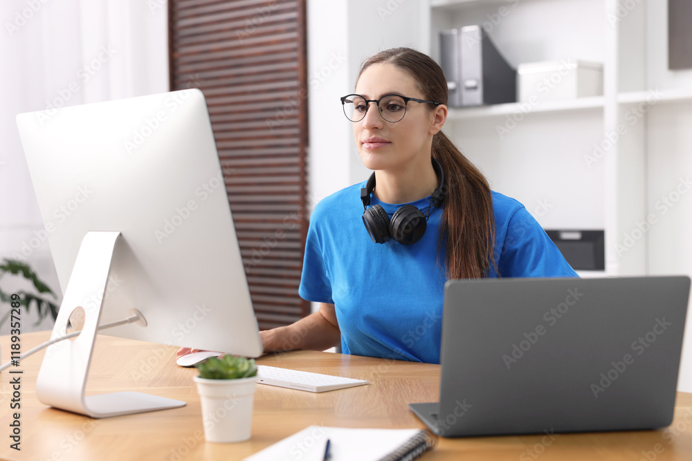 Aufkleber programmer working on laptop and computer at wooden desk indoors