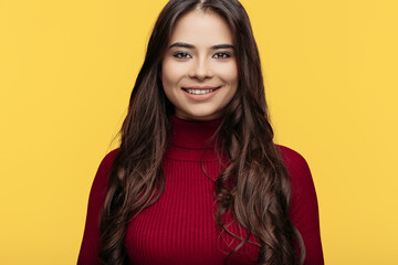 Fototapeta premium Close-up portrait of pretty young woman in red dress is posing on yellow background.