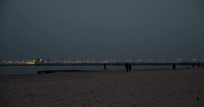 Beach and sea at night with people walking along the shoreline