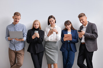 Group of people using different gadgets near white wall indoors. Modern technology