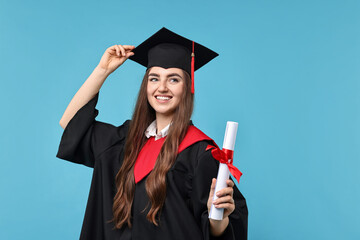 Happy student with diploma after graduation on light blue background