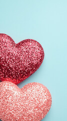 Fototapeta premium Glittery red and coral heart shapes on pastel blue background, evoking love and joy