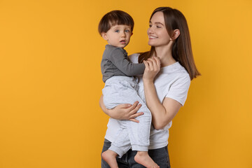 Happy mother with her cute little son on yellow background