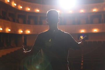 Professional actor rehearsing on stage in theatre, back view