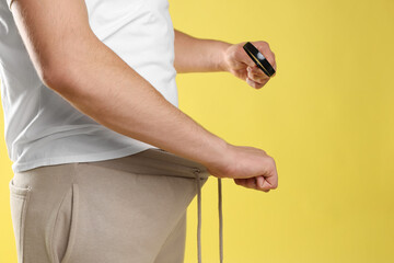 STD (sexually transmitted diseases). Man examining intimate area with magnifying glass on yellow...