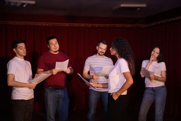 Professional actors with their scripts rehearsing in theatre