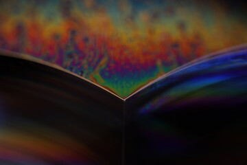 Bright multicoloured reflection of liquid on black background, blue colours, surrealistic pattern	