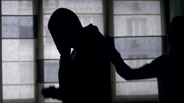 Silhouettes of a sad couple. A woman supports and hugs her upset man. difficulties in relationships. Crisis. Sadness. Family problems