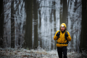 Winter hiking in forest. Man with headlamp walking through dark frosty woodland. Outdoors adventure