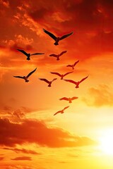Obraz premium dynamic shot of flock of birds flying in formation against dramatic orange sunset sky