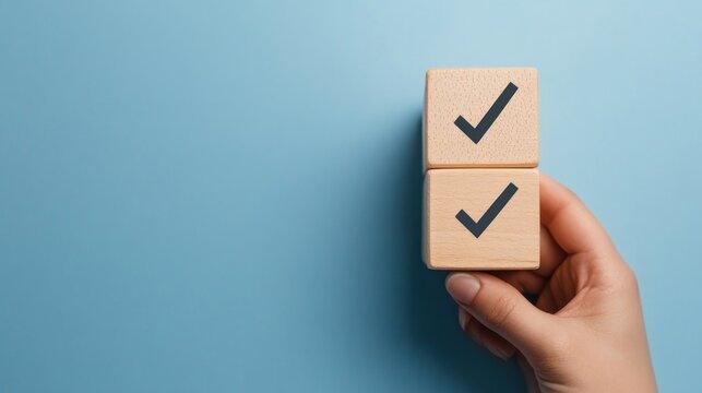 Achieved Goals: Two Checkmarks on Wooden Blocks Held by a Hand Against a Blue Background