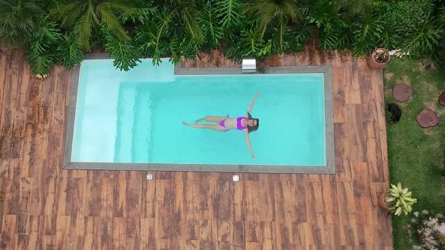 Mulher relaxa em piscina no ver&atilde;o 