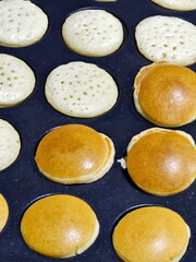 Hands preparing mini pancakes in a mold, they are turned over so that they are completely sewn for breakfast