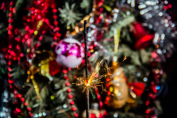Beautiful sparklers with flying sparks burn against the backdrop of a New Year tree