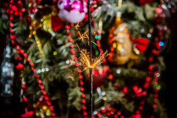 Beautiful small sparklers burn against the backdrop of beautiful decorations on a Christmas tree...