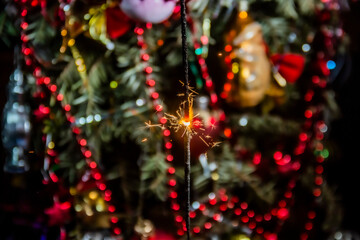 Sparklers burn against the backdrop of beautiful decorations on a Christmas tree during the New...