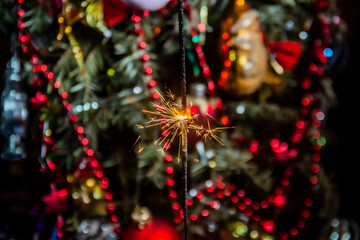 Bengal lights with sparks burn against the background of a beautiful decorated Christmas tree...