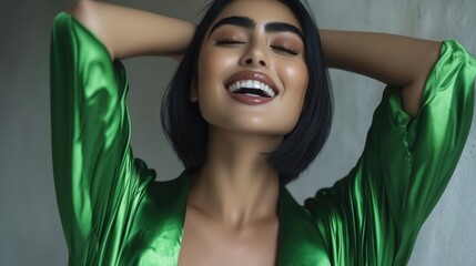 Fototapeta premium Joyful young female in green satin dress with short black hair smiling