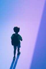 Solitary Boy Walking Away with Backpack Against Purple Background