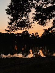 rest in nature outside the city with tents at night. Camping in the forest. Beautiful sunset sky with lights and reflection on the river