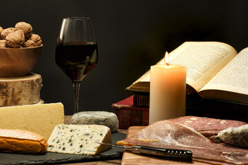 Nature morte avec plateau de fromage, verre de vin rouge, livre et bougie