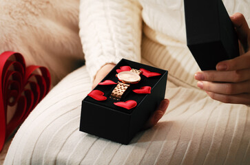 Female hands open a gift with a clock for Valentine Day.