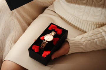 Female hands open a gift with a clock for Valentine Day.