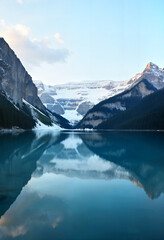 Naklejka premium Lake surrounded by snow-capped mountains at dawn