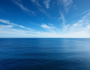 Fototapeta premium the vast expanse of the ocean stretches out before a clear blue sky dotted with wispy white clouds
