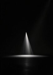 Black and white photograph of a triangular prism in the center of a dark background.