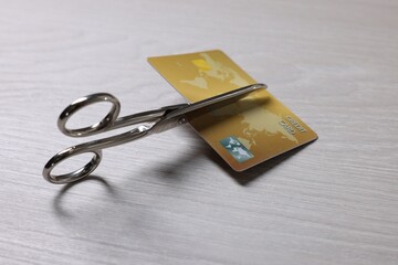 Credit card and scissors on white wooden table, closeup