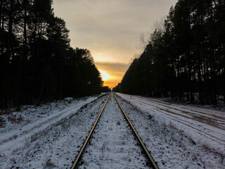 Railway under the snow in the forest at sunset. Rail transport