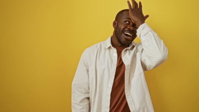 Man in mistake, african american man wearing shirt, standing with hand on head for error on isolated yellow background, forgot memory in moment of realization
