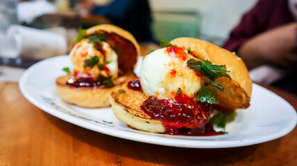 Plate of ice cream burgers garnished with strawberry sauce and herbs