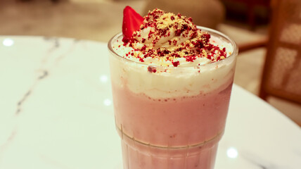 Glass of strawberry smoothie, topped with a frothy layer