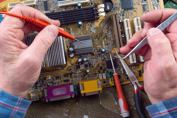 Repair the motherboard in the workshop. Hands of the master, close-up with tools repair...