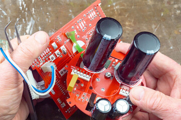This photo shows the hands of an old electronics repairman diagnosing and repairing computer...