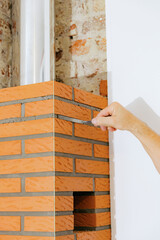 A young man makes brickwork on the chimney of a fireplace.
